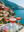 Rose wine being poured into glasses with a scenic background of mountains and sea.